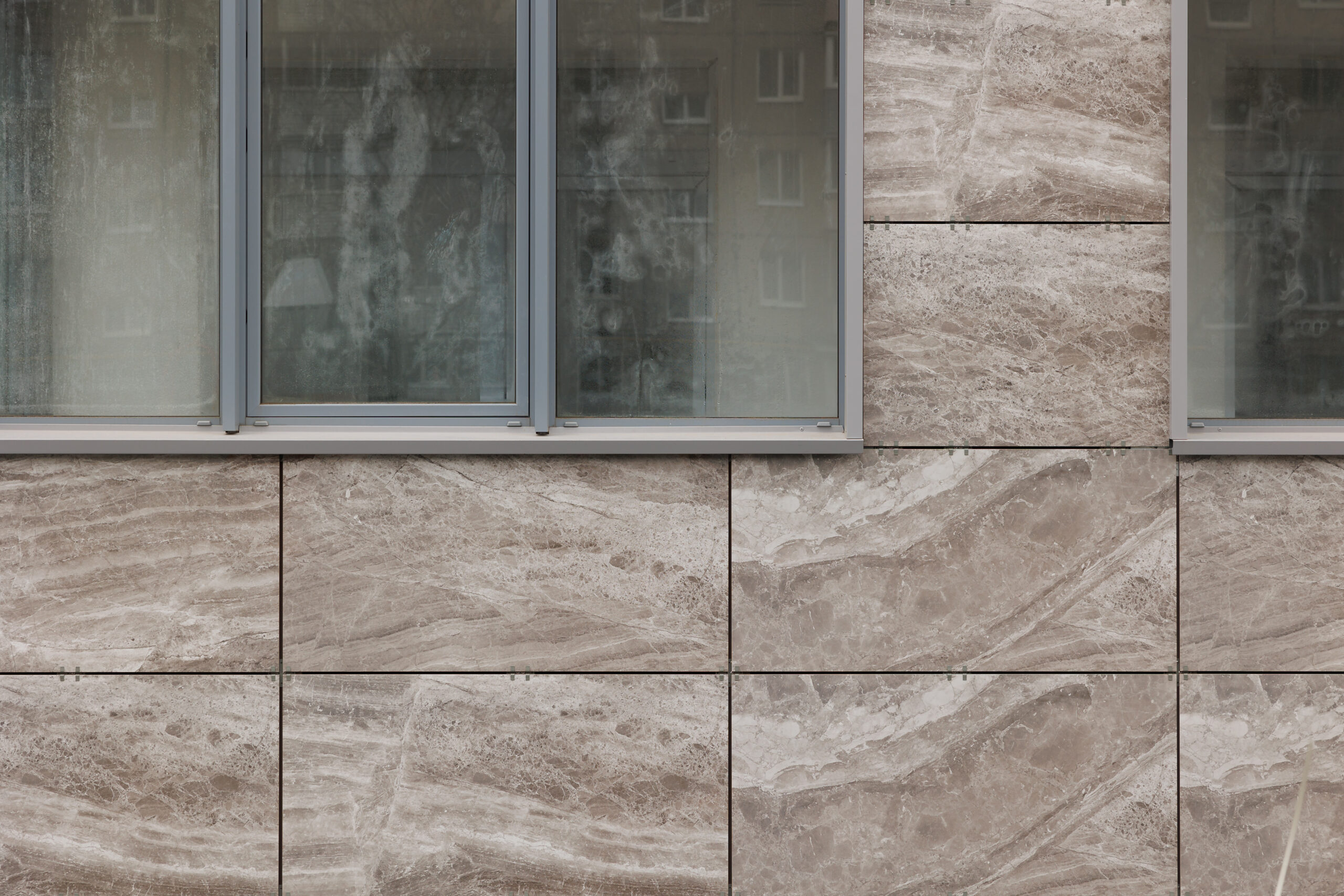 Wall With Window Of Rectangular Smooth Brown Tiles With Rock Slab Texture. Stone Street Covering Of Wall, Masonry Of Building. Stone Panels For Ventilated Walls Or Facades.